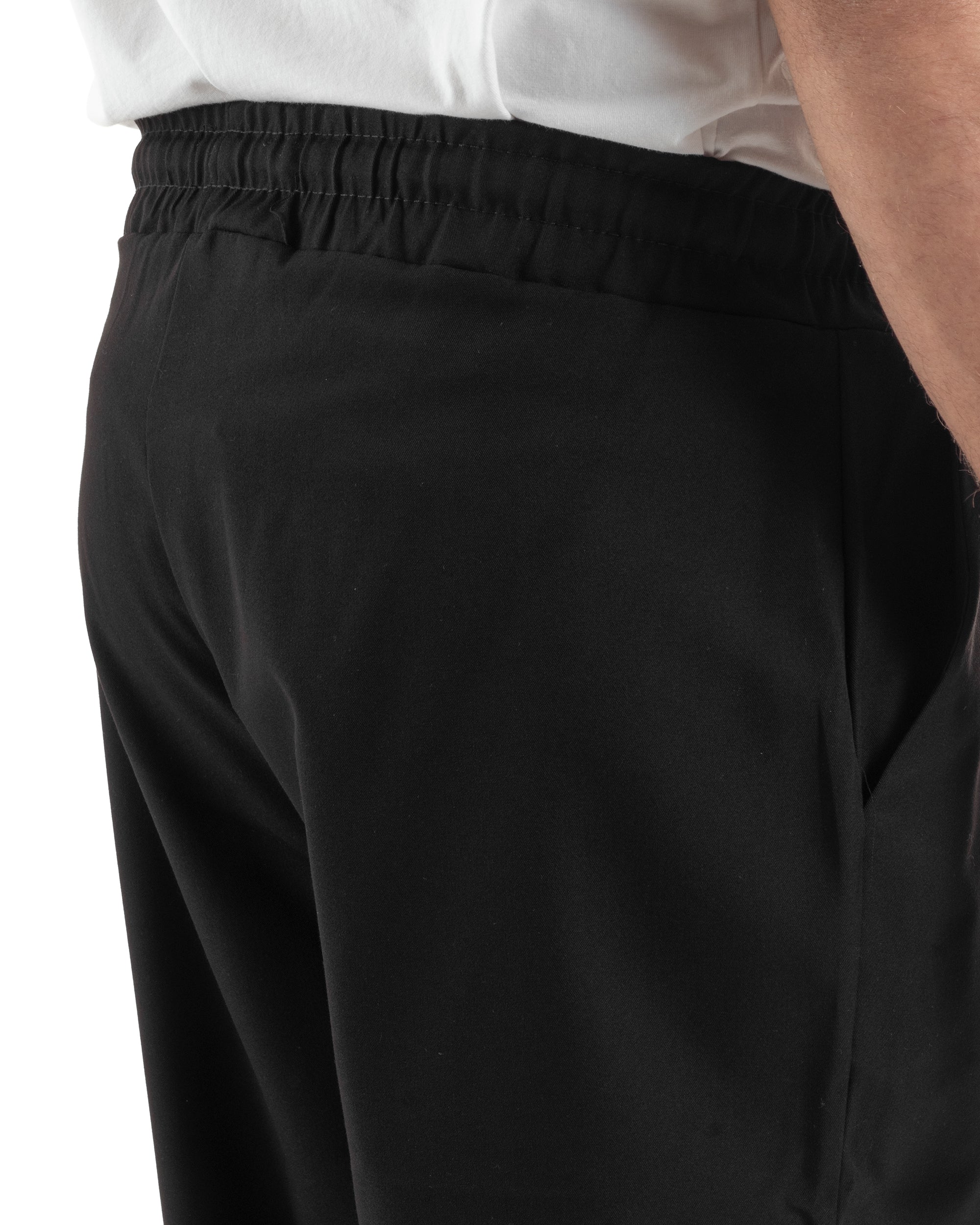 Vista laterale pantaloni uomo nero wide leg fluidi viscosa gamba dritta orlo pulito