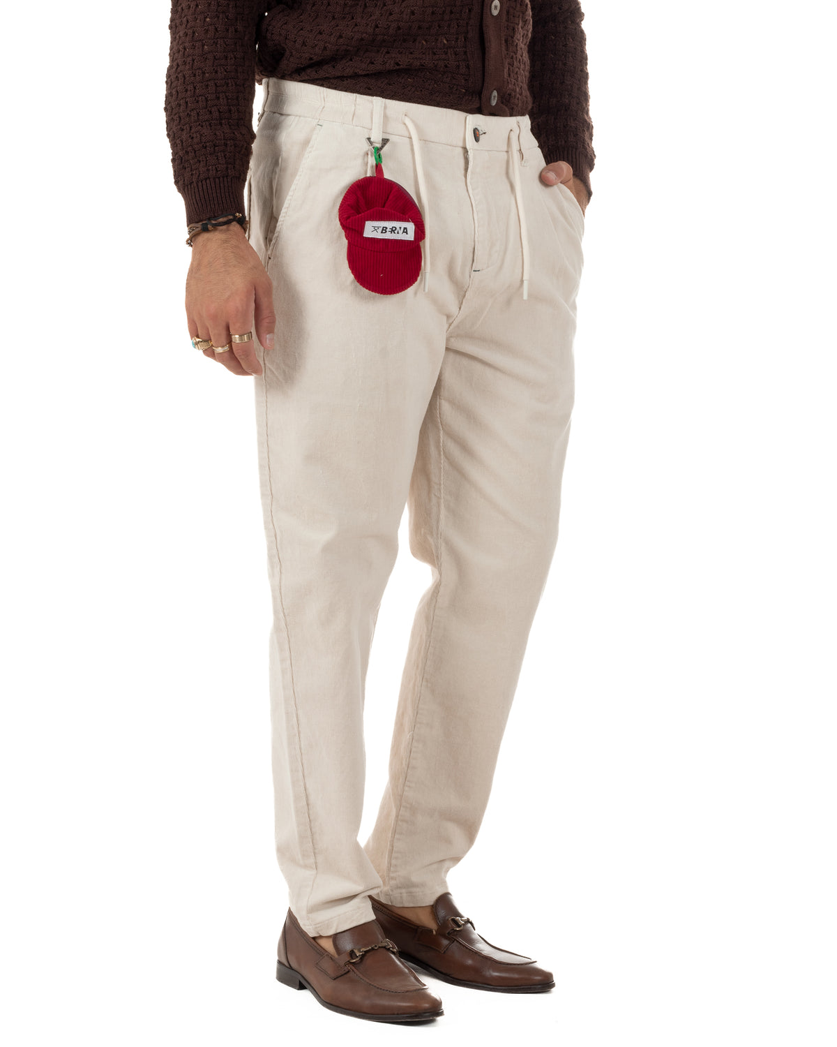 Coulisse chiara e bottone scuro sulla vita dei pantaloni panna , con accessorio rosso agganciato al passante.