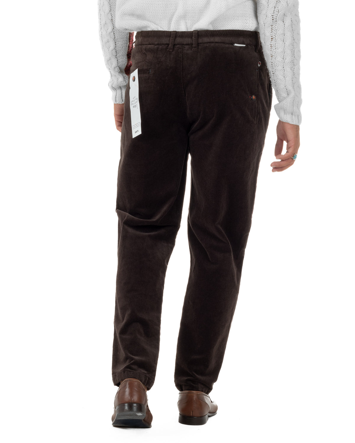 Pantaloni in velluto indossati di spalle, con tasche a filetto e piccoli elementi decorativi.