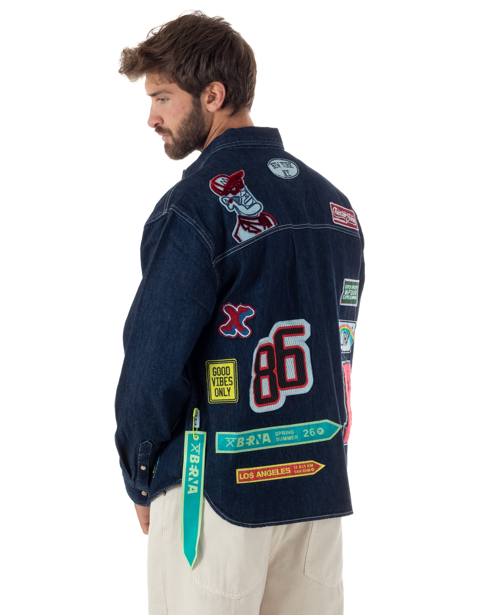 Dettaglio patch ricamati overshirt denim scuro stile boyscout uomo