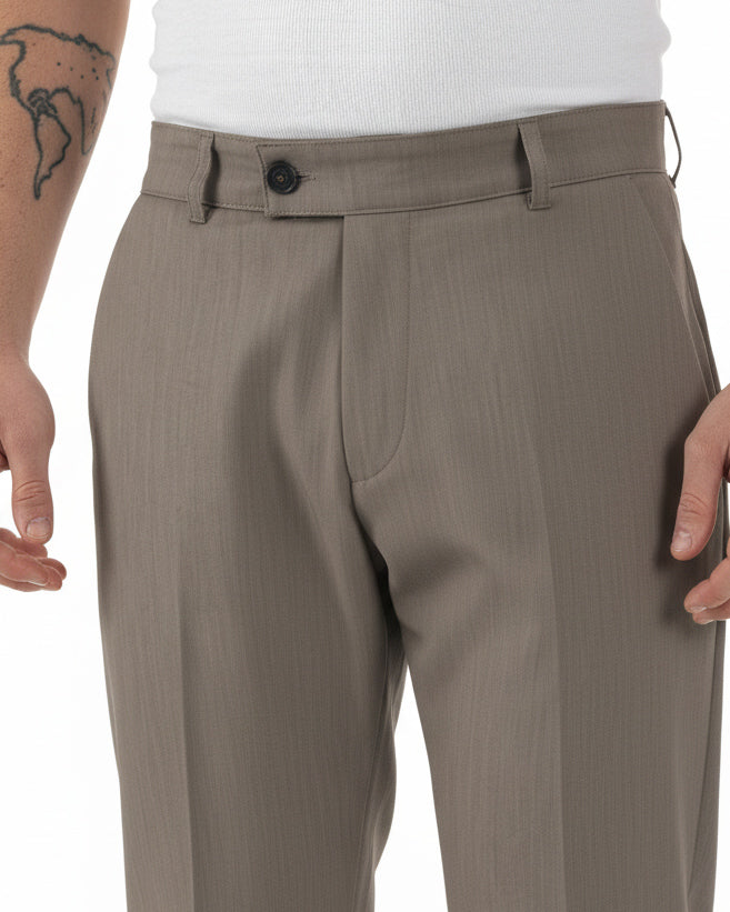 Dettaglio abbottonatura allungata con bottone e zip pantaloni marrone