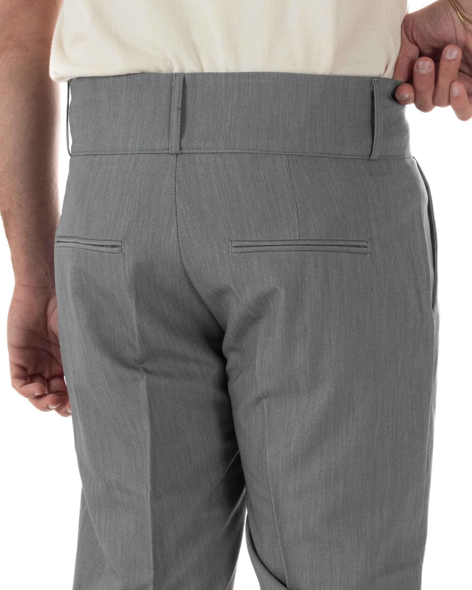Dettaglio bustino vita alta abbottonatura allungata pantaloni grigio uomo