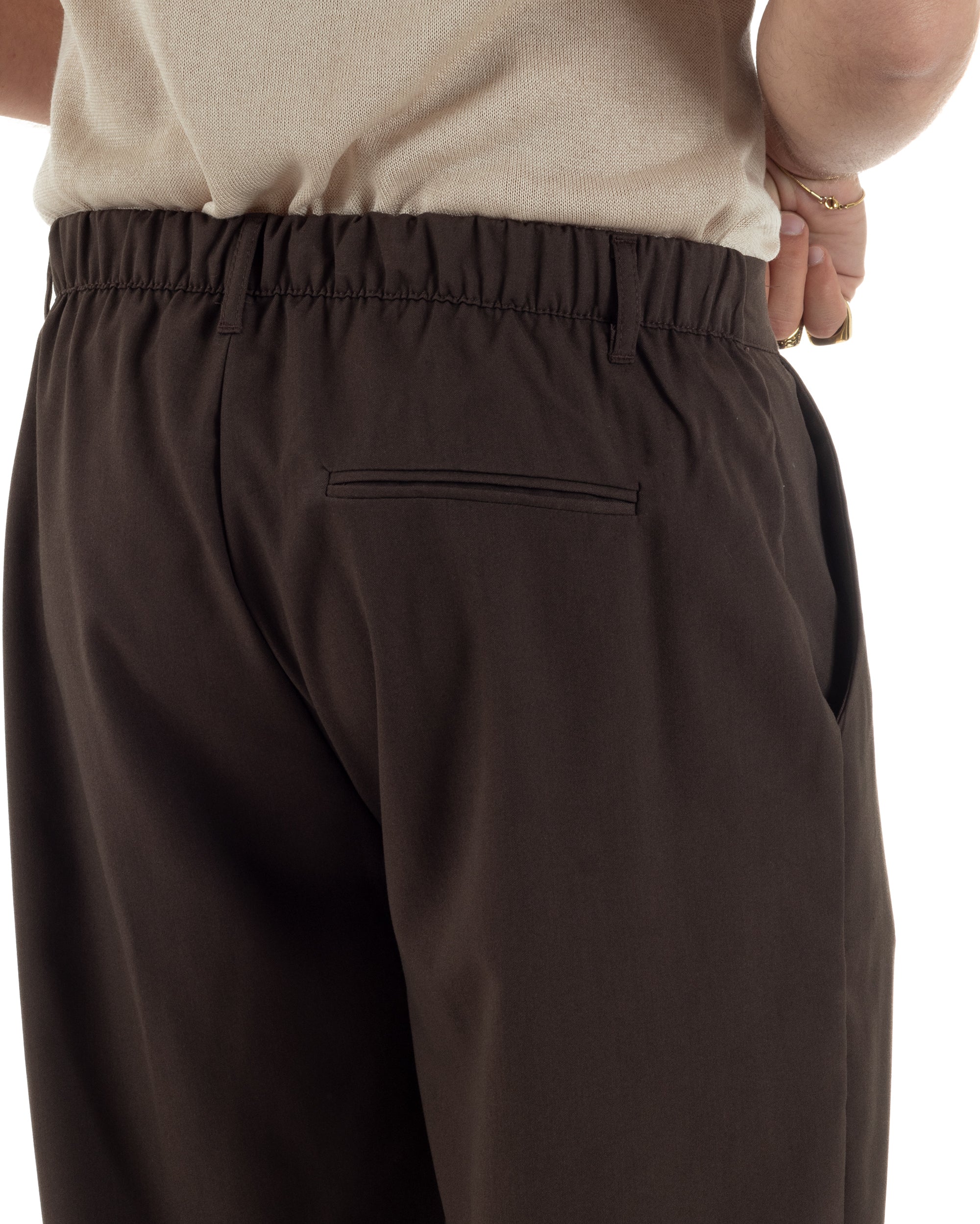 Dettaglio elastico retro e passanti cintura pantaloni marrone baggy uomo