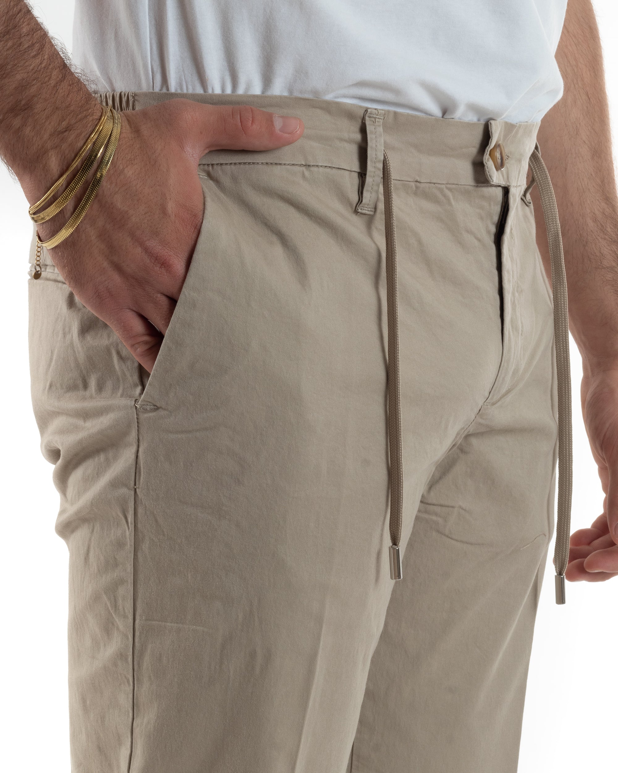 Dettaglio coulisse doppio laccetto piatto terminali metallici bottone dorato pantaloni beige uomo