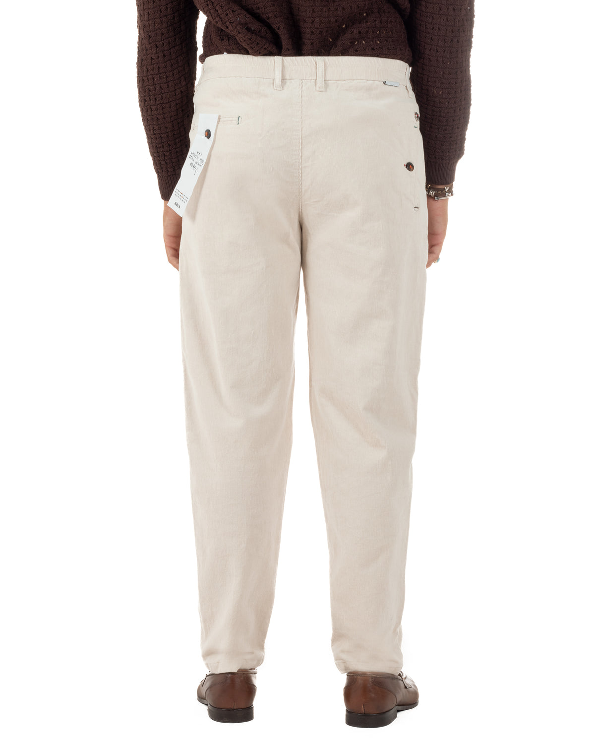 Pantaloni in velluto  indossati di spalle, con tasche a filetto e piccoli elementi decorativi.